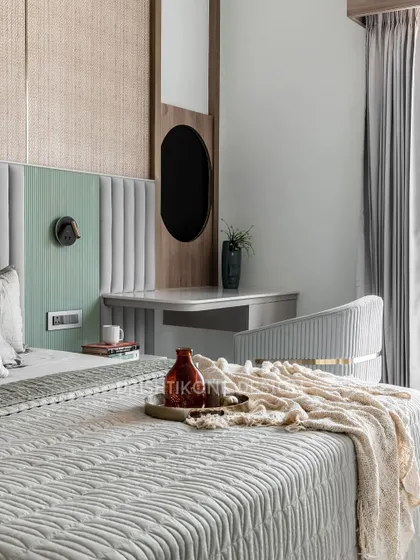 This detail shot shows the integrated vanity area next to the bed. The design features a cane headboard, a plush upholstered chair, and soft lighting, creating a functional and beautiful personal corner.