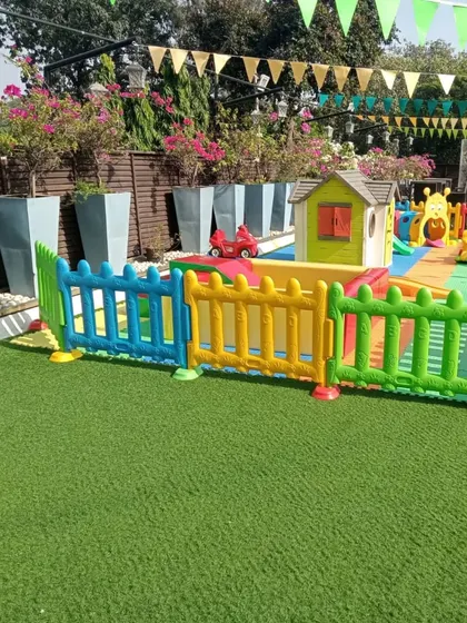 A clean and bright playzone on a sunny day. The setup includes a playhouse and other small toys on artificial turf, perfect for a birthday party or a simple weekend gathering in your backyard.