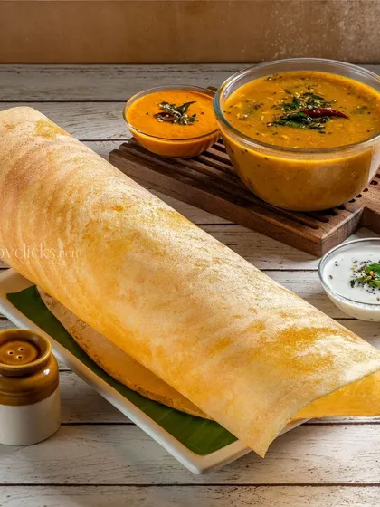 A large, perfectly rolled masala dosa served with sambar and chutney, emphasizing its impressive size and texture.