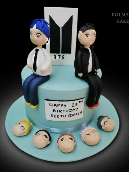 For the BTS army! This cake features two custom fondant figures and the iconic BTS logo, with little fondant heads of the other band members around the base.