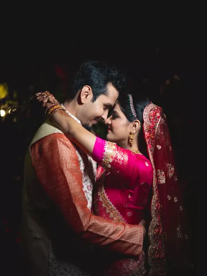 An intimate, low-light portrait of a couple embracing after their wedding, surrounded by darkness to emphasize their connection.