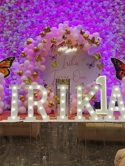 A grand butterfly-themed first birthday on a stage. We used a wall of flowers as the base, adding a balloon arch, large butterfly props, and illuminated letters for a stunning effect.