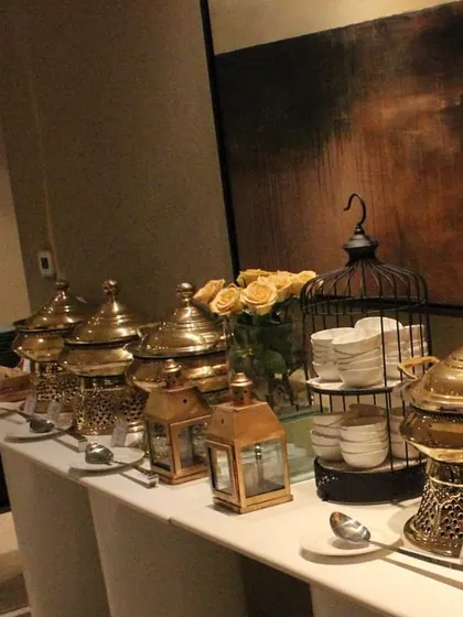 A buffet line featuring our signature brass serving pots, decorated with yellow roses. This setup is perfect for an elegant and personal gathering at home during the winter season.