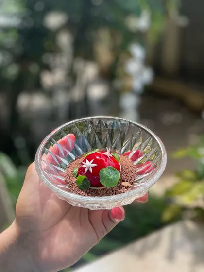 A luxurious Goose Liver Bonbon, coated in a cherry gel and served on a bed of cacao crumbs. A perfect balance of rich, sweet, and earthy flavors.