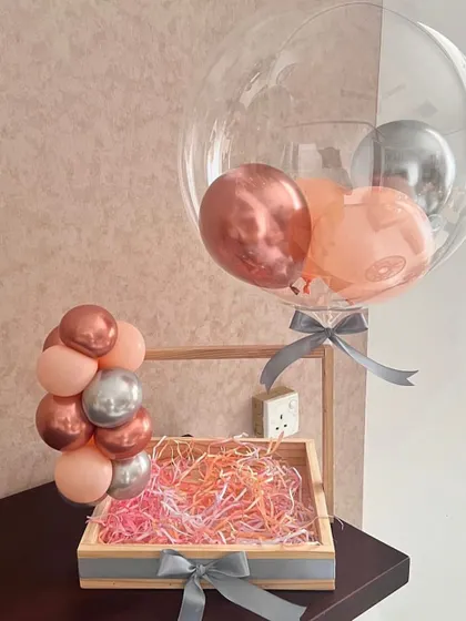 This is the base for one of our custom tray hampers. We use a wooden tray with ribbon details and fill it with colorful shredded paper, ready to be filled with your chosen gifts, and paired with a matching balloon garland.