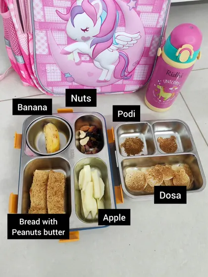A simple and satisfying lunchbox for school. This one includes mini dosas with podi for dipping, bread with peanut butter, apple slices, a banana, and a mix of nuts for a boost of healthy fats and energy.