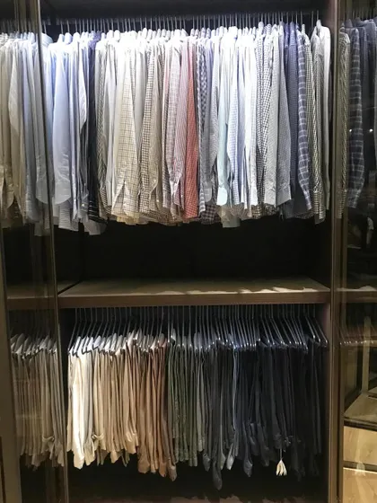 A man's wardrobe, perfectly organized with shirts and trousers hung in separate, color-coded sections. This system makes getting ready in the morning quick and stress-free.