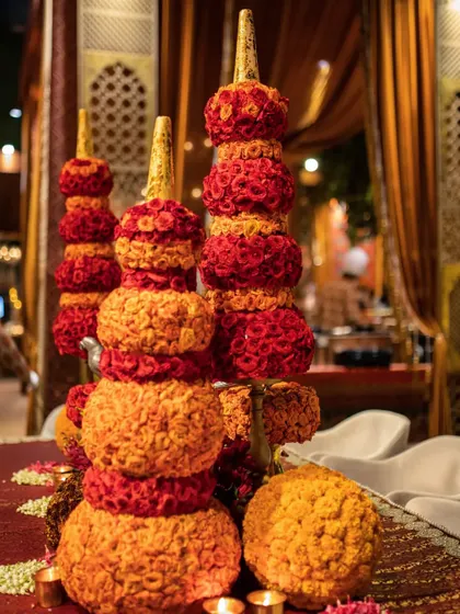 A close-up of the tiered floral sculptures, showing the dense packing of red and orange flowers that creates their solid, architectural form.
