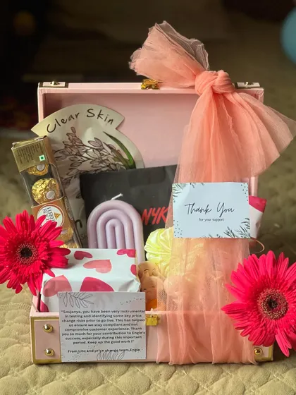 A 'Thank You' hamper designed to pamper and show appreciation. This gift is packed in a pink suitcase box and includes skincare items, a scented candle, and premium chocolates.