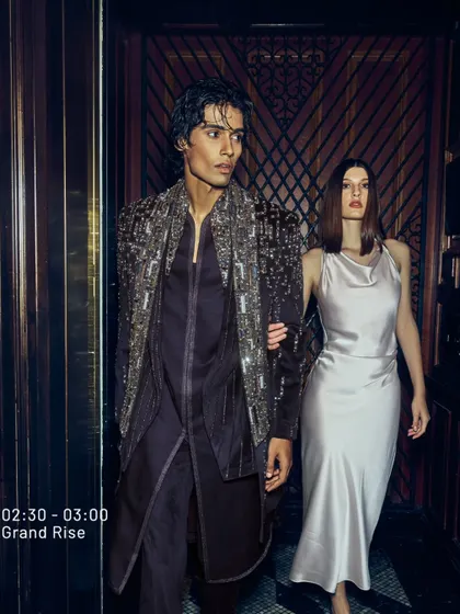 Lively vibes and impeccable style. A man in a deep wine velvet jacket with heavy silver embroidery, paired with a woman in a satin dress. This is how you own the night, together.