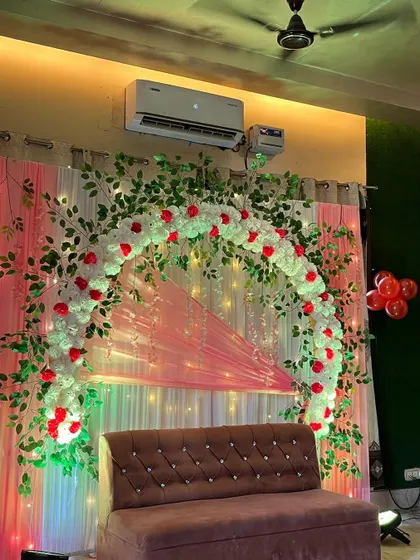 A close-up of the floral arch, made with white flowers, red rose accents, and green leaves.
