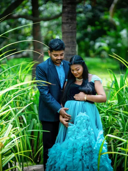 An intimate moment where the couple gently holds the baby bump together, framed by tall green grass. This type of close, connected shot is a signature of our candid maternity photography.