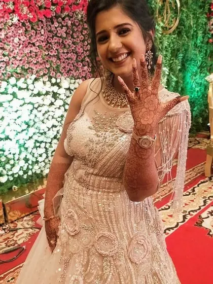 The bride-to-be joyfully displays her engagement mehendi. The intricate floral and vine patterns are perfect for celebrating this special milestone.