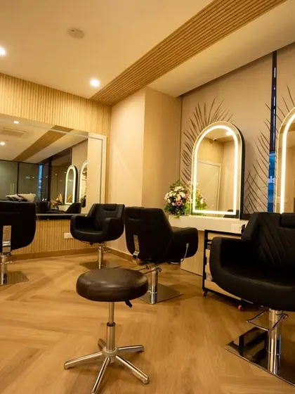This view shows the arrangement of styling chairs and mirrors, designed for both client comfort and stylist efficiency. The herringbone-patterned flooring and subtle wall details contribute to the salon's modern yet timeless aesthetic.