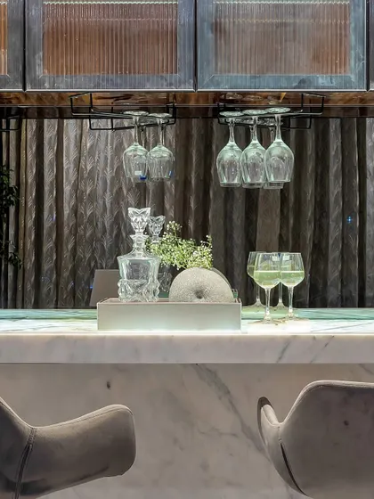 A close-up of a home bar, ready for an evening of entertaining. Crystal decanters, elegant glassware, and a marble countertop create a sophisticated and functional space for mixing drinks.