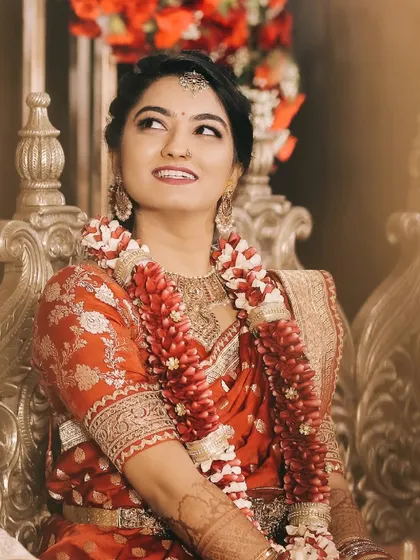 A candid shot of the bride, her upward glance filled with joy and anticipation. The flower garland adds a touch of traditional charm.