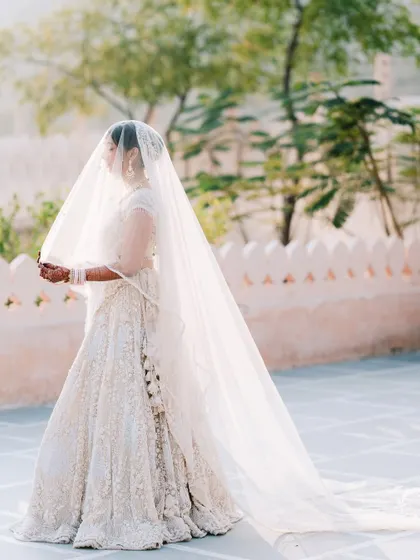A breathtaking bridal portrait with a long, flowing veil. This shot is all about grace and elegance, creating a timeless and dramatic image against the Pushkar landscape.