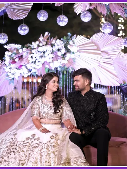 A dreamy Sangeet portrait. The couple looks elegant against a boho-chic backdrop with pampas grass and disco balls.
