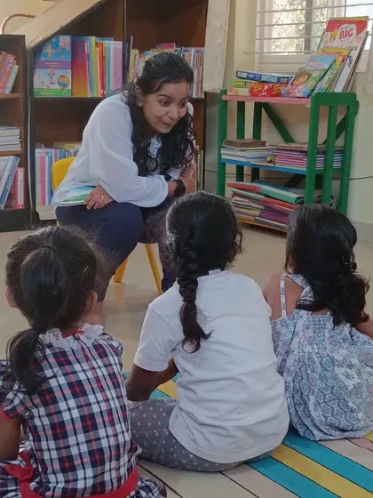 A storyteller leans in to share a secret from the story about Leela the butterfly. This intimate setting helps even the youngest children feel connected and engaged.