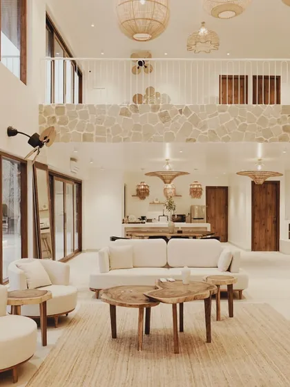 A view from the mezzanine level shows how the different spaces in Artha Villa connect. The stone-clad balcony overlooks the main living area, creating a visual link between the upper and lower floors while maintaining a sense of openness.