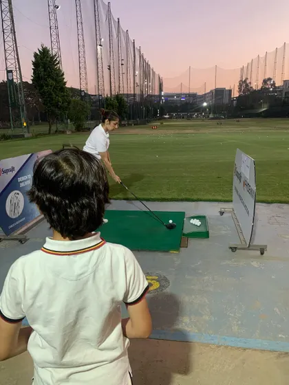 A young golfer watches intently as an adult practices her putting. It's great to see the next generation learning from others at the course.