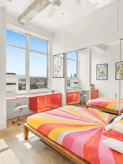 In this New York apartment's guest room, we used a vibrant Marimekko-style textile to bring a burst of colour and energy. A custom-designed desk and drawers in a glossy red lacquer run the length of the window, creating a functional and cheerful workspace.