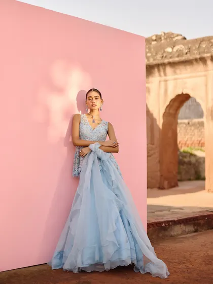 A full-length view of a powder blue lehenga with intricate silver embroidery. The styling is soft and romantic, with a flowing dupatta, making it an ideal look for a daytime wedding or bridesmaid.