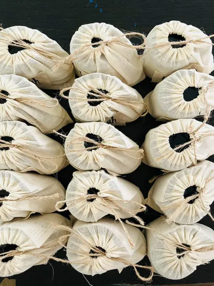 An overhead view of a bulk order, with each product carefully wrapped in a hand-stamped muslin pouch. It's a beautiful way to present a natural, handmade gift.