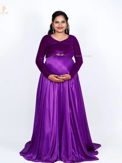 A full-length view of the purple maternity gown, showing how the satin skirt drapes elegantly to the floor. This gown is a great option for a formal studio photoshoot.
