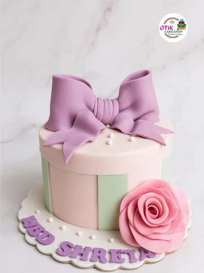 We designed this cake to look like a beautiful gift box. The pastel pink and green stripes, oversized lilac bow, and handcrafted sugar rose create a truly special birthday surprise.