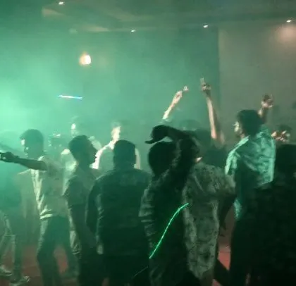 The dance floor is filled with smoke and green light, creating a high-energy vibe.
