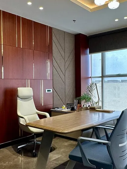 The executive office design balances natural light from the large windows with the warm tones of the wood-paneled wall.