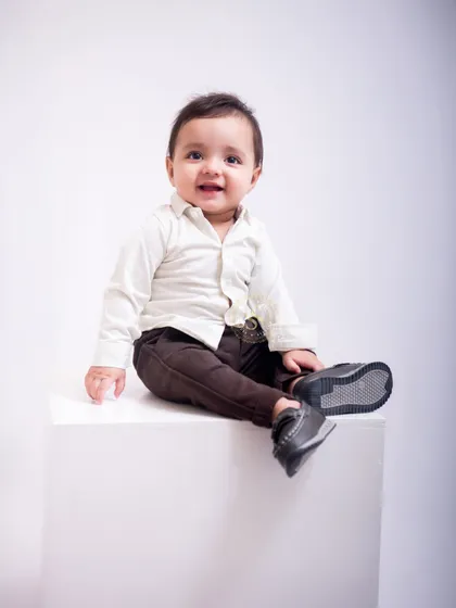 A stylish little one strikes a relaxed pose. Using a simple white block and background, we create clean, modern portraits that focus entirely on your child's personality.