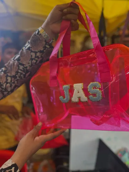A happy customer showing off her personalized pink jelly bag with her initials 'JAS'.