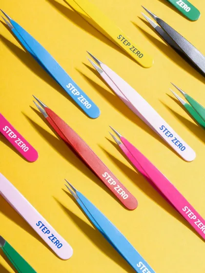 A dynamic, colorful flat lay of Step Zero tweezers. The repetitive pattern and bright yellow background create a visually arresting image for social media and e-commerce banners.