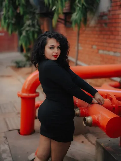 A portrait of a model in a black dress, leaning against bright red pipes. The color contrast and industrial setting make for a very strong and memorable fashion image.