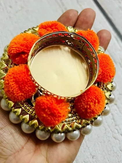 A close-up of the orange pom-pom tea light holder, showing the pearl details and craftsmanship.