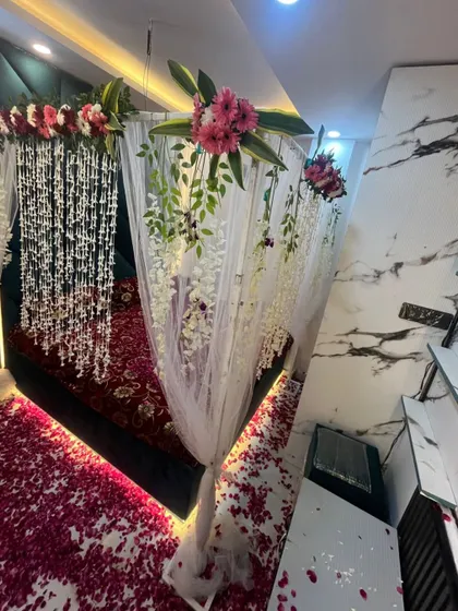 An angled view of the decorated room, showing the hanging floral canopy, draped curtains, and the romantic lighting under the bed.
