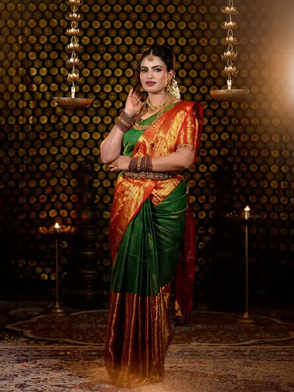 A complete look at a traditional South Indian bride in a stunning green and red Kanjivaram silk saree. The makeup features defined eyes, a bold matte lip, and a flawless base that complements the antique gold jewelry.