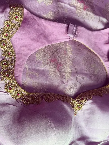 A flat-lay view of a lavender blouse with a large, dramatic keyhole back, perfect for a bride who wants to make a statement.