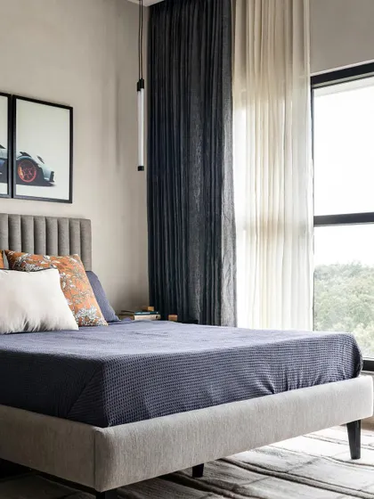The son's room in the same home has a more modern, clean vibe with concrete-textured walls. The space is personalized with framed car posters, reflecting his interests.