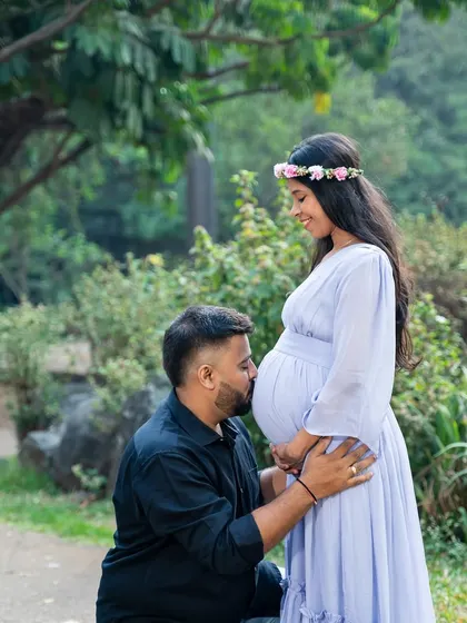 A tender moment of connection. The father-to-be kisses the baby bump, a classic and heartfelt pose that I love to capture during maternity sessions in a natural park setting.