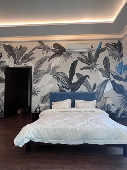 The magic of black. This monochrome tropical mural uses shades of black, white, and grey with a pop of blue to create a dramatic and highly sophisticated bedroom feature wall.