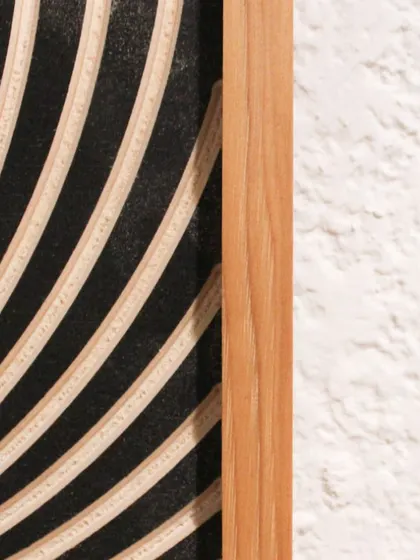 A detail shot of our carved 'Black Hole' wall hanging, showing the edge of the natural wood frame and the swirling carved lines.
