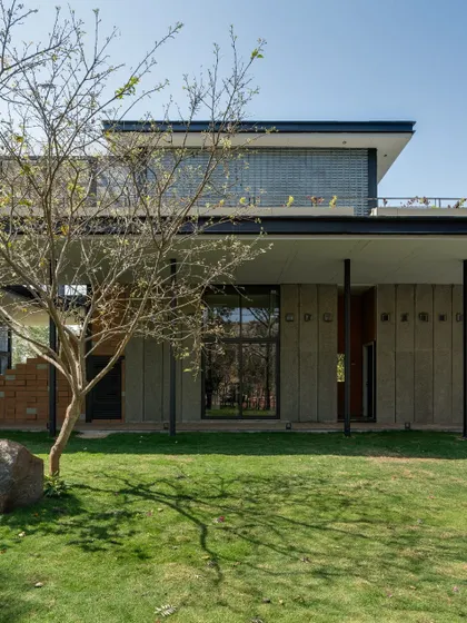 The clean lines of the architecture are softened by the presence of a young tree in the foreground. We believe in designing spaces that allow nature to grow and intertwine with the built form over time.