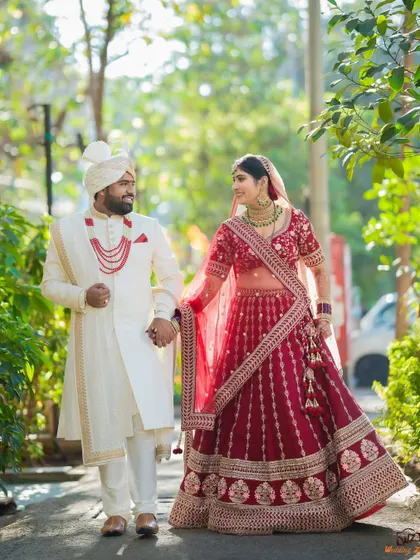 A candid walking shot of a Sindhi couple, capturing their natural interaction and the grandeur of their wedding outfits.
