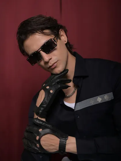 Another look from the Cairon campaign, combining a modern striped shirt with edgy accessories like sunglasses and driving gloves to embody the "young money" aesthetic.
