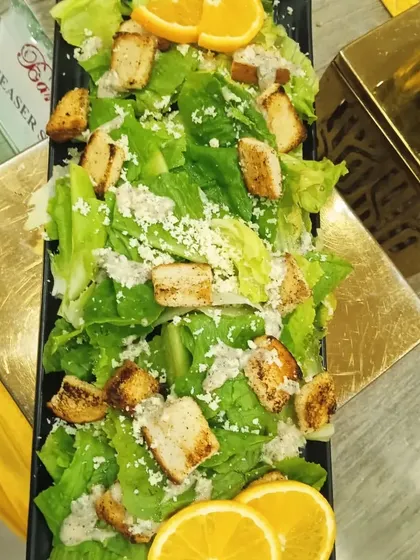 A top-down view of my Caesar salad, showing the crisp lettuce, croutons, and parmesan, garnished with fresh orange slices.