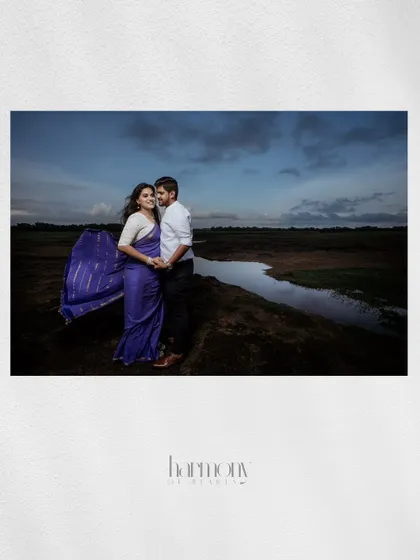 An artistic album layout of the couple in a field, with the wind catching the bride's saree, captioned "Harmony of Hearts."
