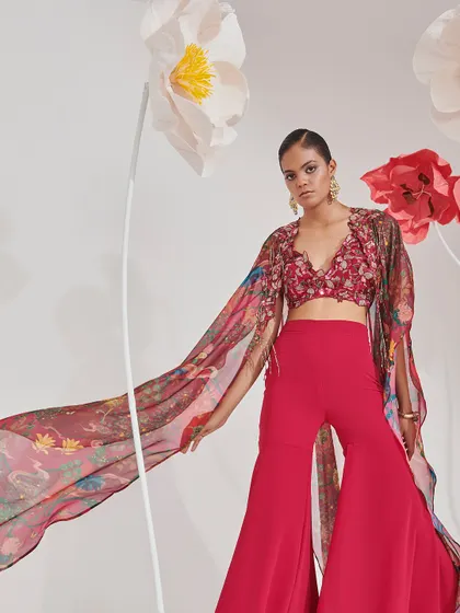 A vibrant pink ensemble featuring flared pants and a dramatic printed cape. This is a perfect example of fusion wear that is both comfortable and stylish for a Mehendi or Haldi ceremony.